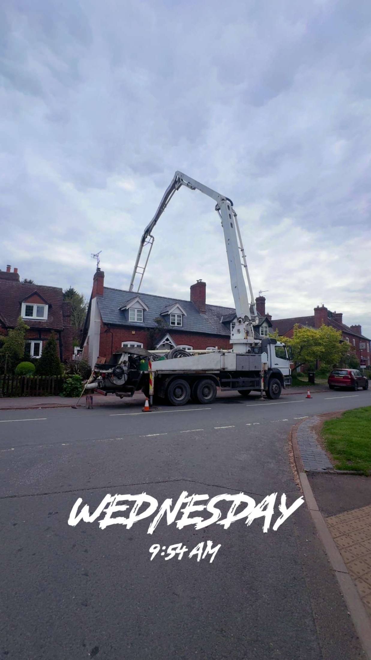 Concrete boom pump reaching over a residential street